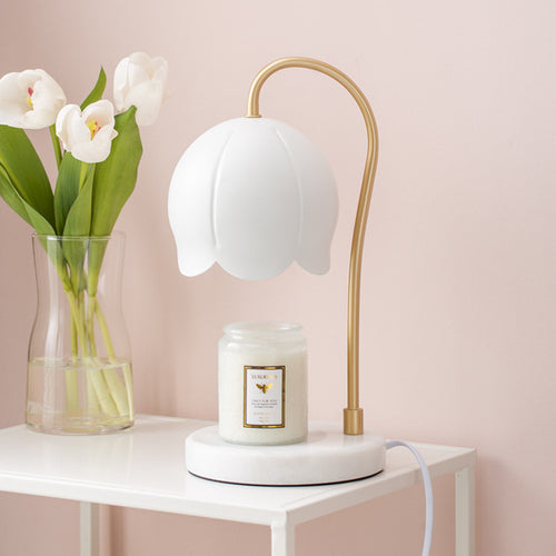 Decoratieve tafellamp van Eriks-shop met keramische basis en zachte verlichting op een houten tafel.